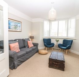 A living room with a grey sofa and blue chairs around a wooden chest in Cool Stone Cottage Instow near Bideford