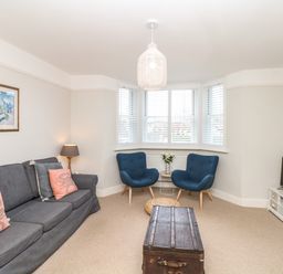 A living room with a gray sofa and blue chairs around a wooden trunk as a coffee table at Cool Stone Cottage Instow near Bideford