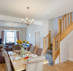 A dining table set with plates and sunflowers in a living room with leather sofas and wooden stairs at The Crab Shell in Appledore near Bideford