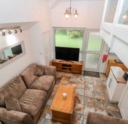 A living room with a sofa and television at Trelessy Lodge near Amroth