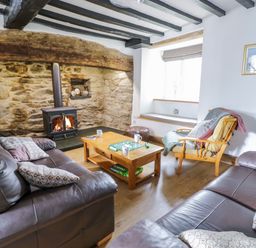 A living room with two leather sofas a wood stove and a wooden coffee table with a game at Tai Ucha in Cerrigydrudion