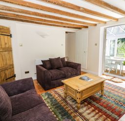 A living room with two sofas a wooden coffee table a patterned rug and a dining area visible through an open door at Blenheim Edge The Causeway Woodstock