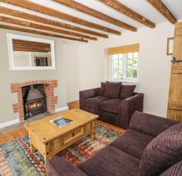 A living room with two sofas a wooden coffee table a fireplace and exposed wooden beams at Blenheim Edge The Causeway in Woodstock
