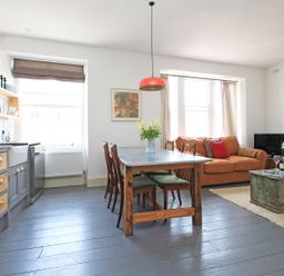 An open plan kitchen and living area with a dining table and chairs an orange sofa and a coffee table at Star House in Marazion