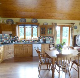A kitchen with wooden cabinets a dining table with chairs and flowers a jukebox at Maifield in Carrick-On-Suir County Tipperary