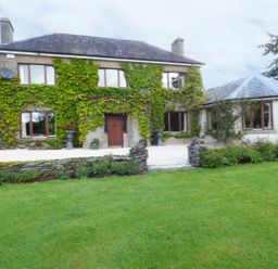 A stone house with ivy on the walls and multiple windows in a garden at Maifield in Carrick-On-Suir County Tipperary