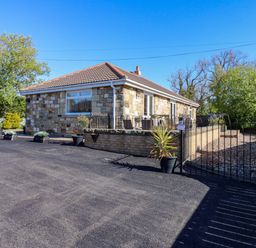 A house with stone exterior and driveway at Blacksmiths Cottage in Shilbottle