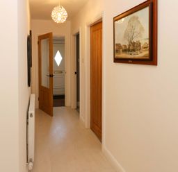 A hallway with a light fixture and paintings at Blacksmiths Cottage in Shilbottle