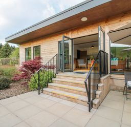 An outdoor patio with stairs leading to an open room with chairs and a table at No1 The Lodge in Acton near Bishops Castle