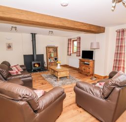 A living room with leather sofas a wood burning stove and wooden furniture at Pentre Fawr in Llandrindod Wells
