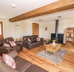A living room with leather sofas a wooden coffee table on a rug and a fireplace at Pentre Fawr in Llandrindod Wells