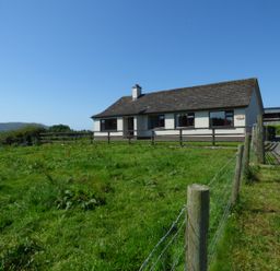 A single story house with a fenced grassy yard and a gravel driveway at Nephin View in Foxford County Mayo