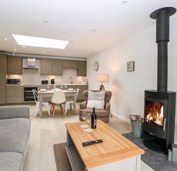 A living room and kitchen with a fireplace sofa armchair dining table and kitchen cabinets at Rabbit's Warren in Titchfield Common