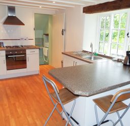 A kitchen with countertops stools stove oven sink and window at The Granary in Walford near Ross-on-Wye