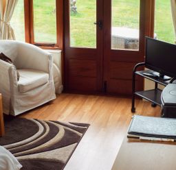 A living room with an armchair a rug and a TV on a stand at The Granary in Walford near Ross-on-Wye