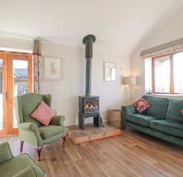 A living room with armchairs sofa a wood burning stove and wooden floor at Stoney-Brook Lodge in Bedlam near Ludlow