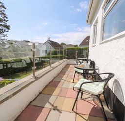 A balcony with tables and chairs at Bay View in Benllech