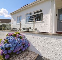 A house exterior with flowers and chairs at Bay View in Benllech