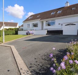 A house with a garage and flower bed at Bay View in Benllech