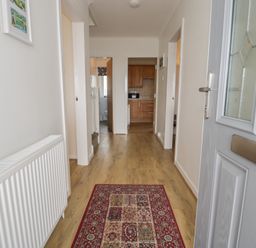 A hallway with a door and access to kitchen and bathroom at Bay View in Benllech