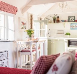 A kitchen and dining area with a table, chairs, shelves with kitchen items, and a microwave at The Snug in Rescorla near St Austell
