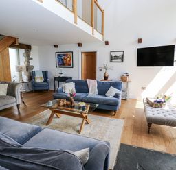 A living room with a television and staircase at Crane Field Laithe in Otterburn, North Yorkshire