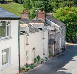 A row of houses along a street with flower pots and greenery at 3 Horse Pool Road in Laugharne