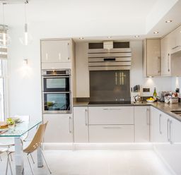 A kitchen with a glass dining table and chairs and modern cabinets at No 6 Arlington Villas in Ilfracombe