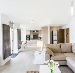 An open-plan living room and kitchen with a beige sofa and a dining table at No 6 Arlington Villas in Ilfracombe