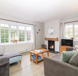 A living room with sofas a coffee table a fireplace and large windows at Glan Dwr in Red Wharf Bay