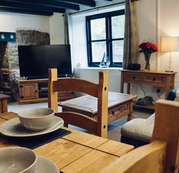 A living room with wooden furniture bowls on a table and a television at Easterly Cottage in Bude