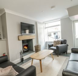 A living room with black leather sofas a wooden coffee table a fireplace and a television at Ivy Bank in Windermere
