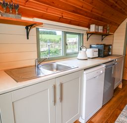 A kitchen countertop with a sink dishwasher kettle toaster and microwave at Meadow View in Rhayader