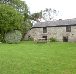 A garden with chairs and a table outside a stone cottage at Old Winery Cottage Golant near Fowey