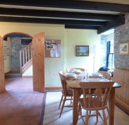 A dining room with a wooden dining table and chairs set for a meal near a window at Old Winery Cottage Golant near Fowey
