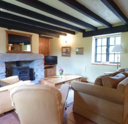 A living room with armchairs a sofa a wooden coffee table a stone fireplace and a window at Old Winery Cottage Golant near Fowey