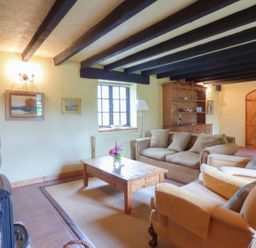 A living room with a sofa set wooden coffee table and wooden cabinet at Old Winery Cottage Golant near Fowey