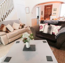 A living room with two sofas and a table with flowers at Corbett Cottage in New Haggerston near Holy Island