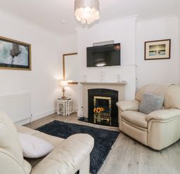 A living room with leather armchairs a fireplace and a mounted TV at Pier View in Paighton