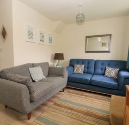 A living room with two sofas a lamp a mirror and framed pictures on the wall at 104 Sunrise Drive in Filey
