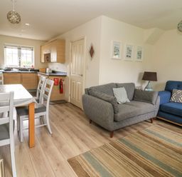 An open plan living room and kitchen with dining table chairs sofas and a striped rug at 104 Sunrise Drive in Filey