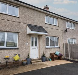 A pebble dash house front with a white door two windows and outdoor seating at Gwynfa in Rhyd Uchaf near Bala Gwynedd