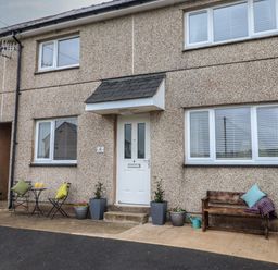 The front of a house with a white door two windows outdoor seating and potted plants at Gwynfa Rhyd Uchaf near Bala Gwynedd