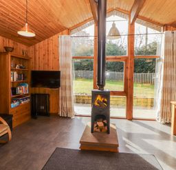 A living room with a wood stove and bookshelf at 26 Dukes Meadow in Greystoke near Penrith