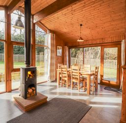 A dining room with a stove and wooden dining table at 26 Dukes Meadow Greystoke near Penrith