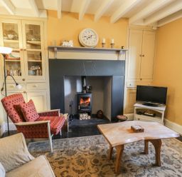 A living room with a fireplace armchairs a wooden coffee table television and built in cupboards at Miners Cottage in Blaenau Ffestiniog