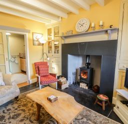 A living room with armchairs a wooden coffee table and a fireplace at Miners Cottage in Blaenau Ffestiniog