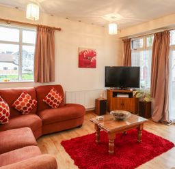 A living room with a red sectional sofa red cushions a wooden coffee table and a television at The Cabin in Combe Martin