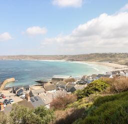 A coastal village with houses parked cars a stone pier and a sandy beach at Sennen Heights in Sennen Cove near Penzance