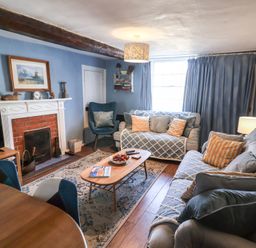 A living room with a sofa and armchair at Delphinium in Blakeney, Norfolk